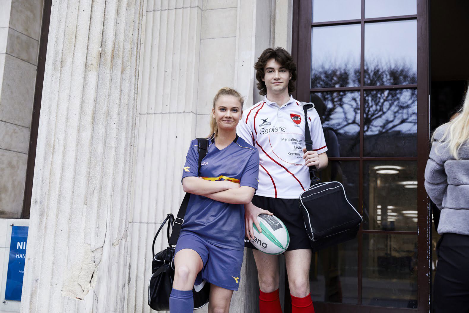 To elever med foran bygning