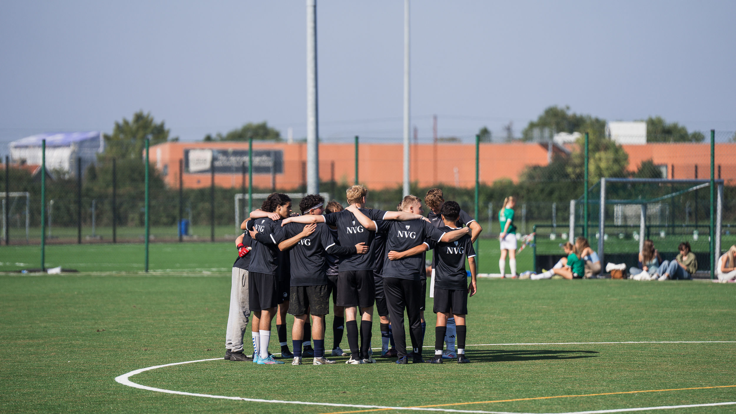 Elever står i rundkreds på en fodboldbane til Niels Brock Cup