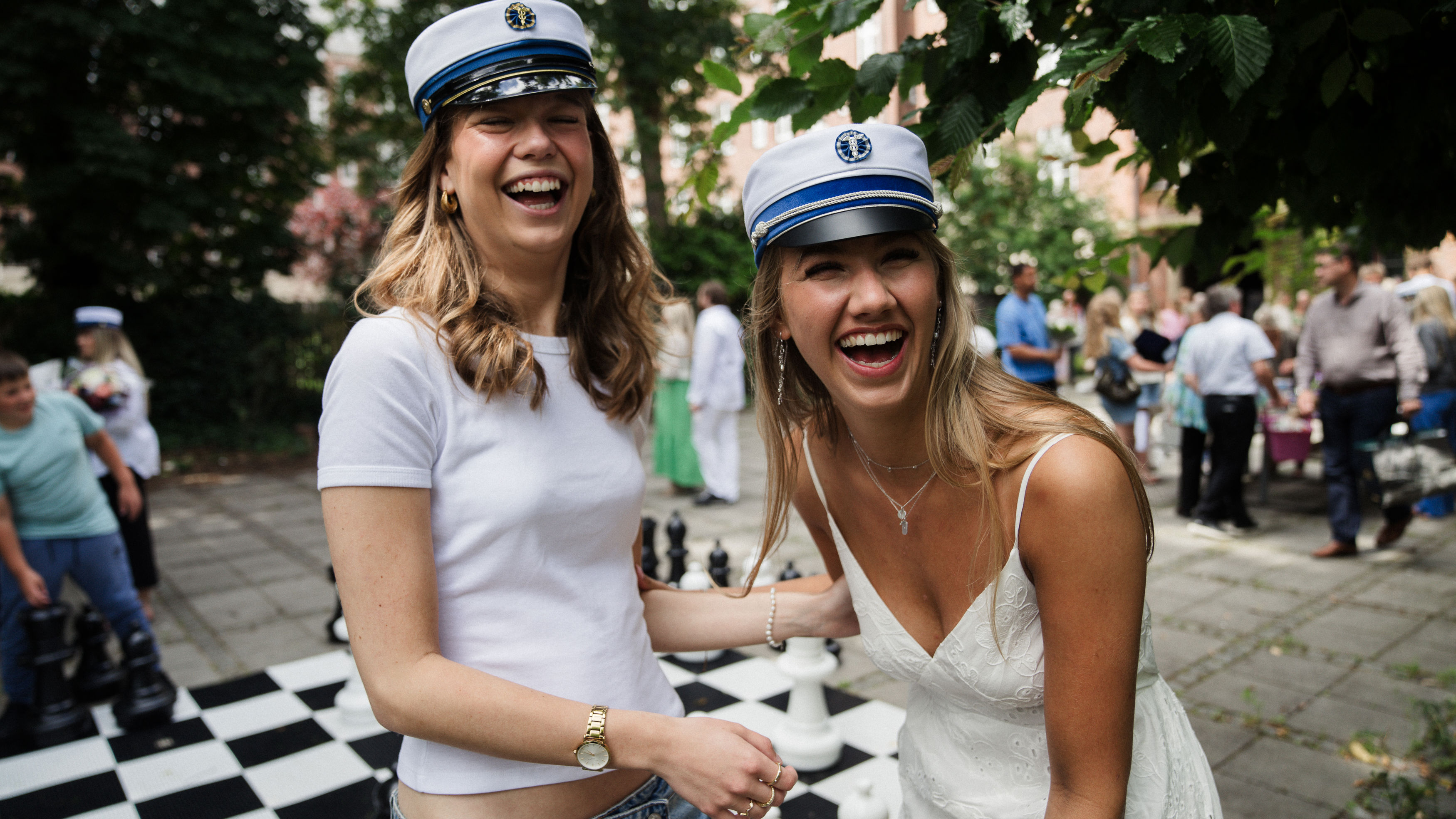 To elever med studenterhue på står og griner