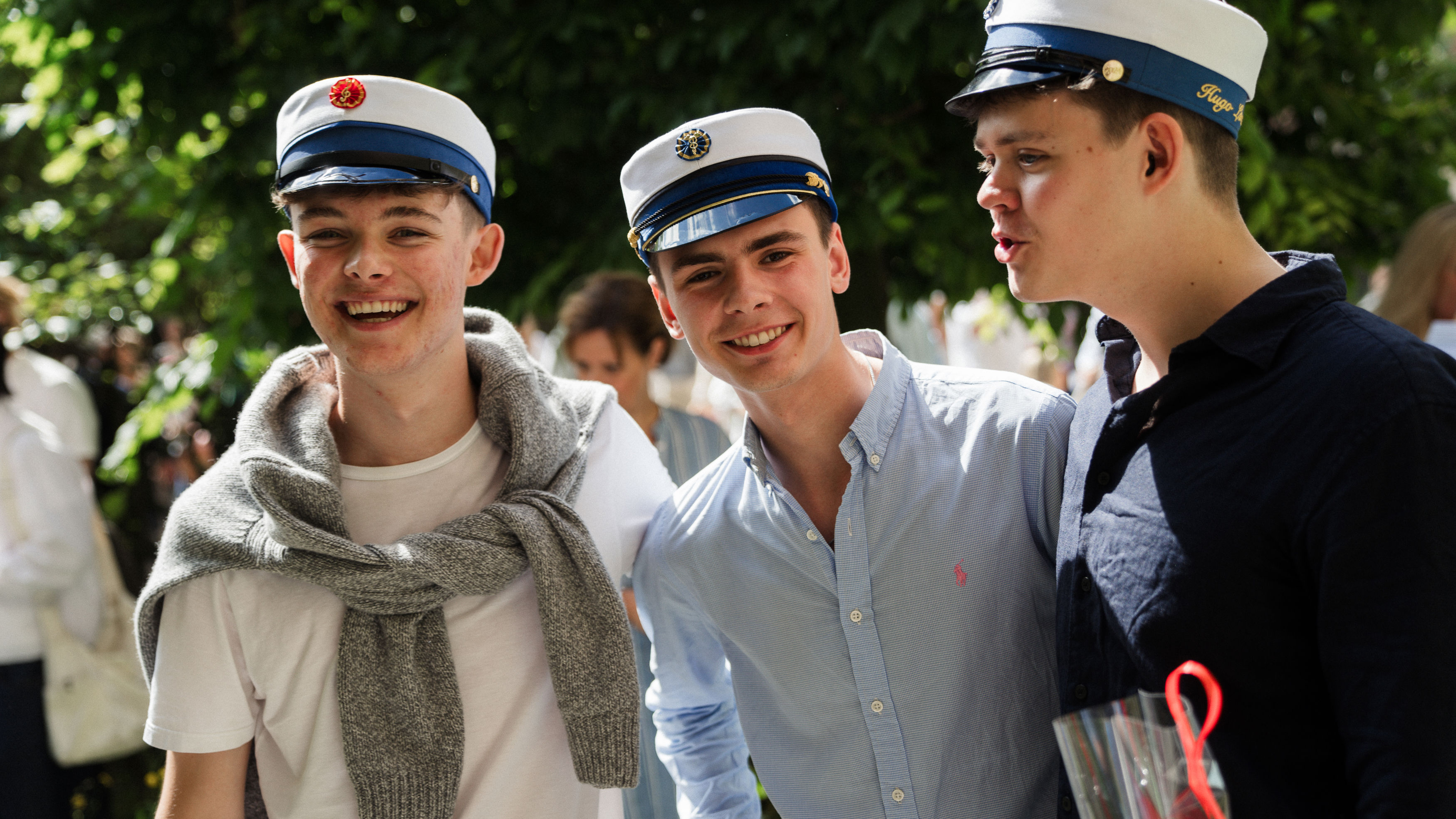 Elever står med studenterhuer på og har en samtale